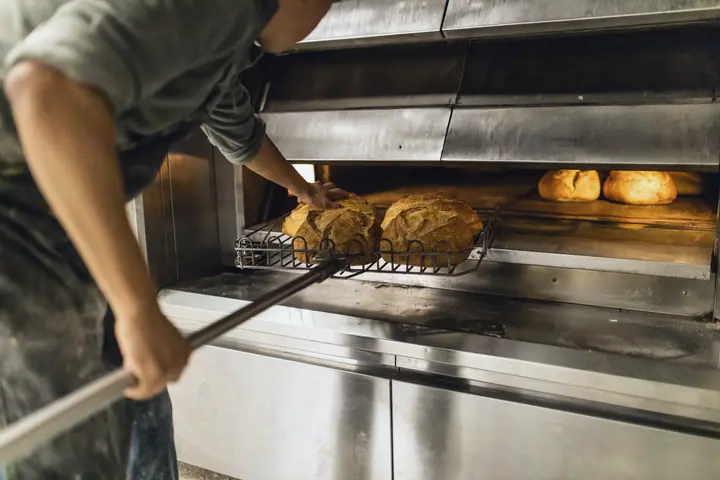 Baker pulls bread from the deck oven with a peel