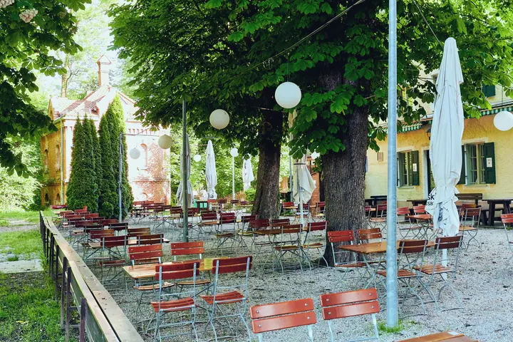 Empty beer garden with red chairs under chestnut trees