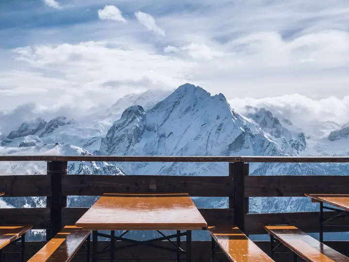 Empty wooden terrace of a mountain hut in front of snow-covered peaks