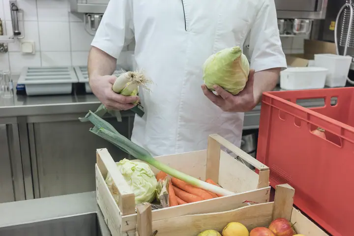 A cook checks vegetables from the crate at goods-in
