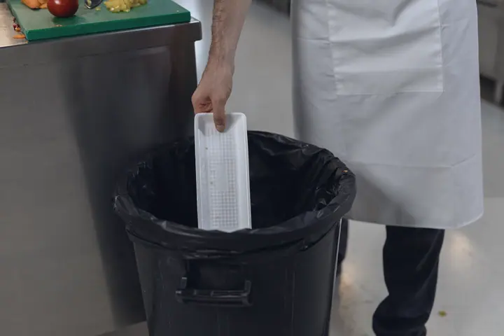 An empty container goes into the waste bin with a bin bag