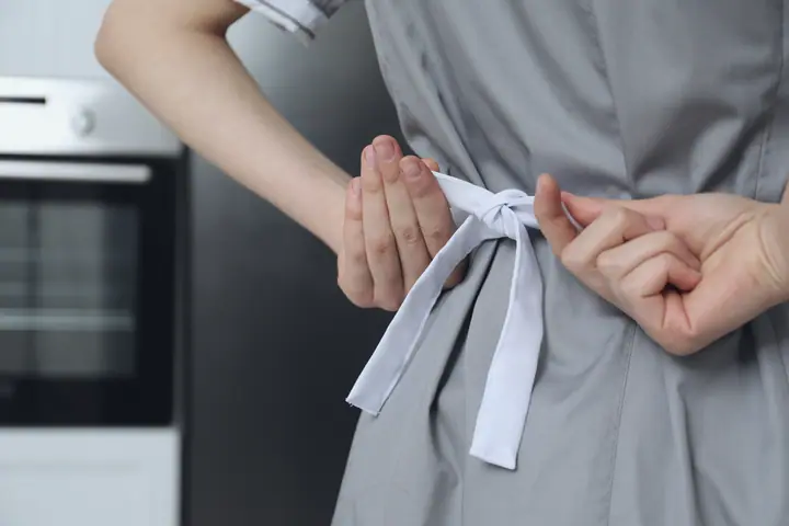 Hands tie an apron at the start of the shift